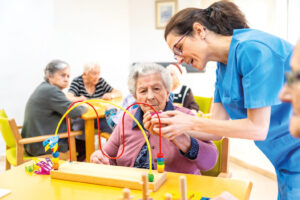 Senior woman and caregiver playing skill board games at geriatrics