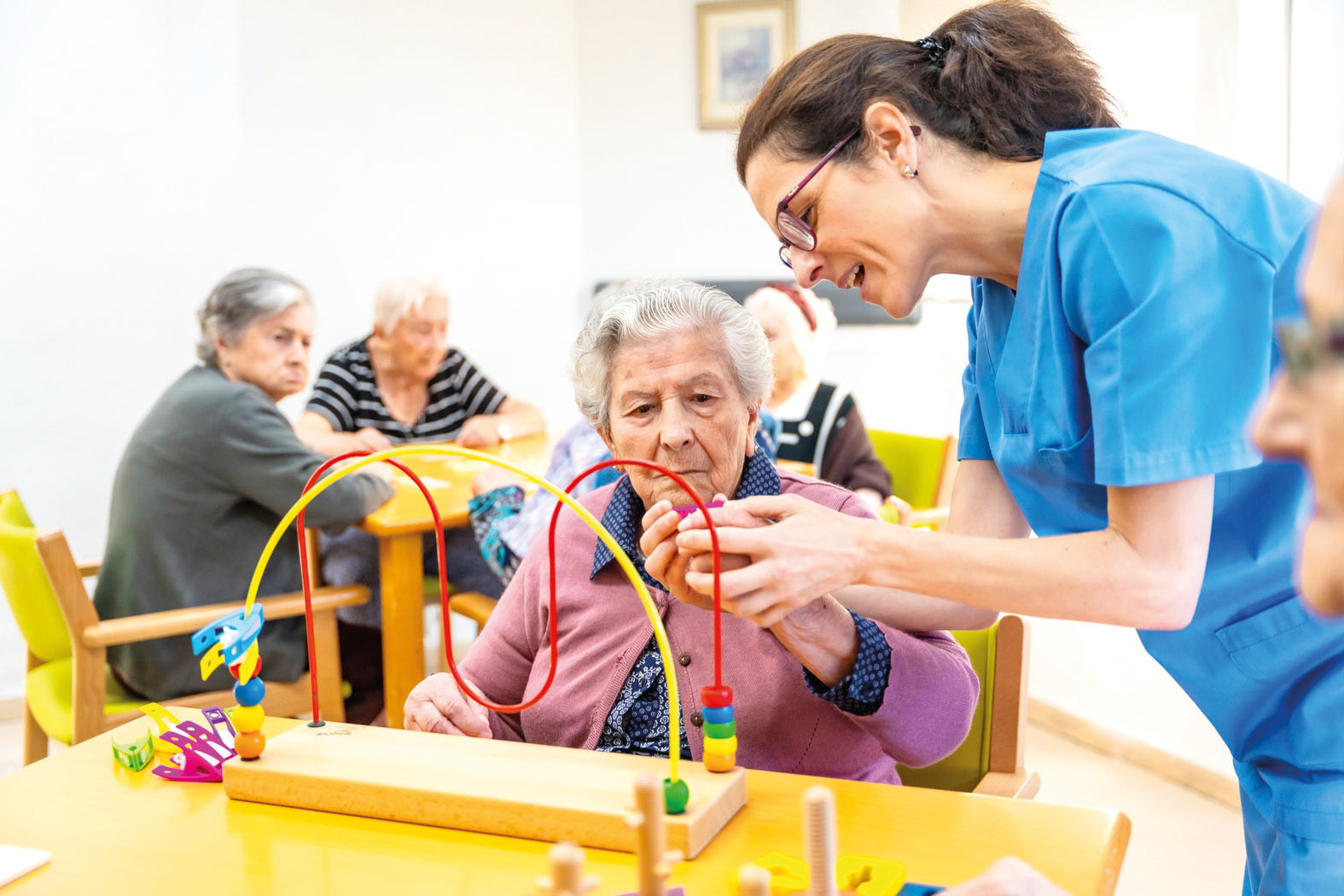 Senior woman and caregiver playing skill board games at geriatrics